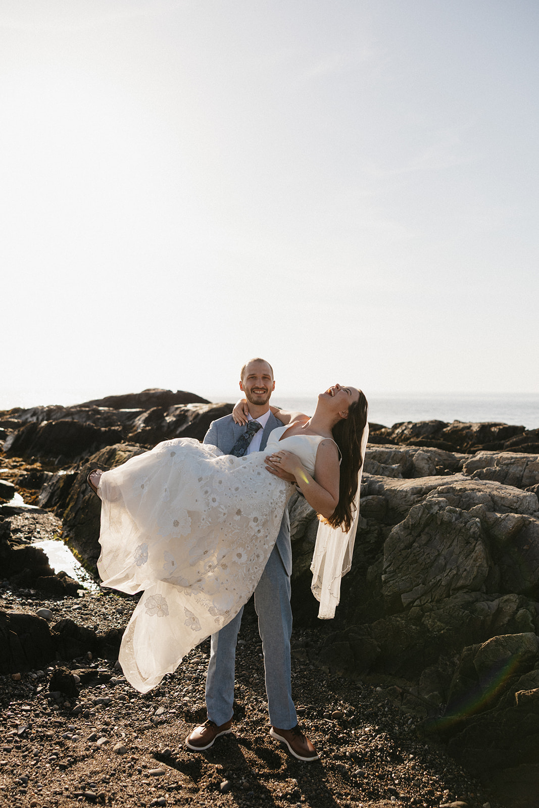 bride and groom laugh and share a moment on the beach