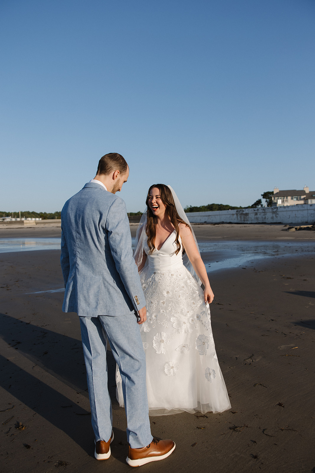 bride and groom share candid romantic moments during their first look session on the New Hampshire beach