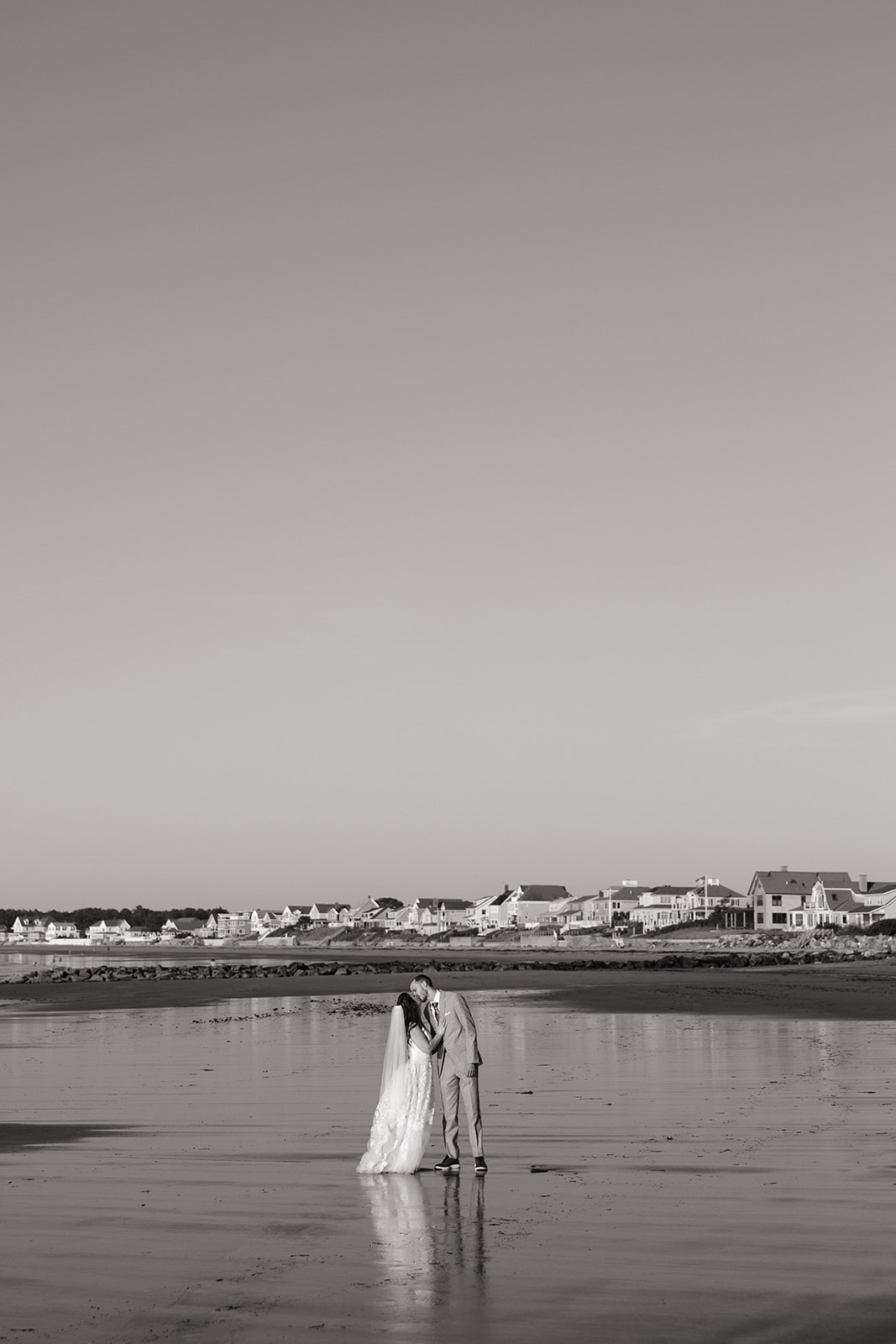 bride and groom share candid romantic moments during their first look session on the New Hampshire beach