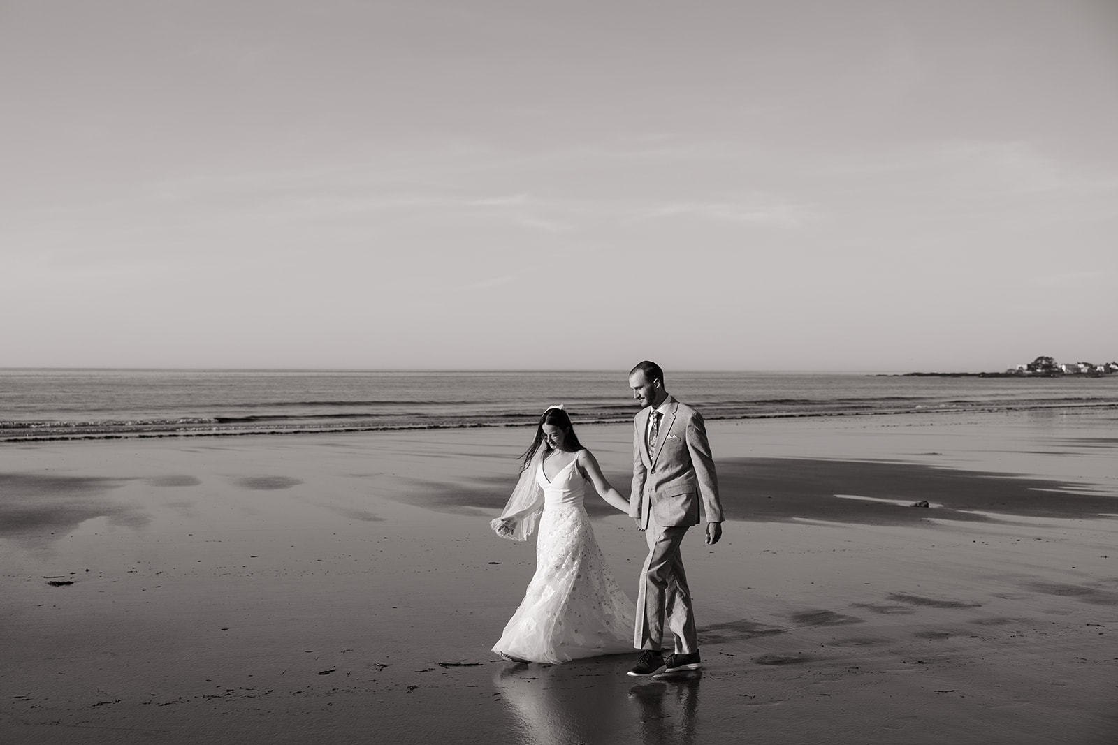 bride and groom share candid romantic moments during their first look session on the New Hampshire beach