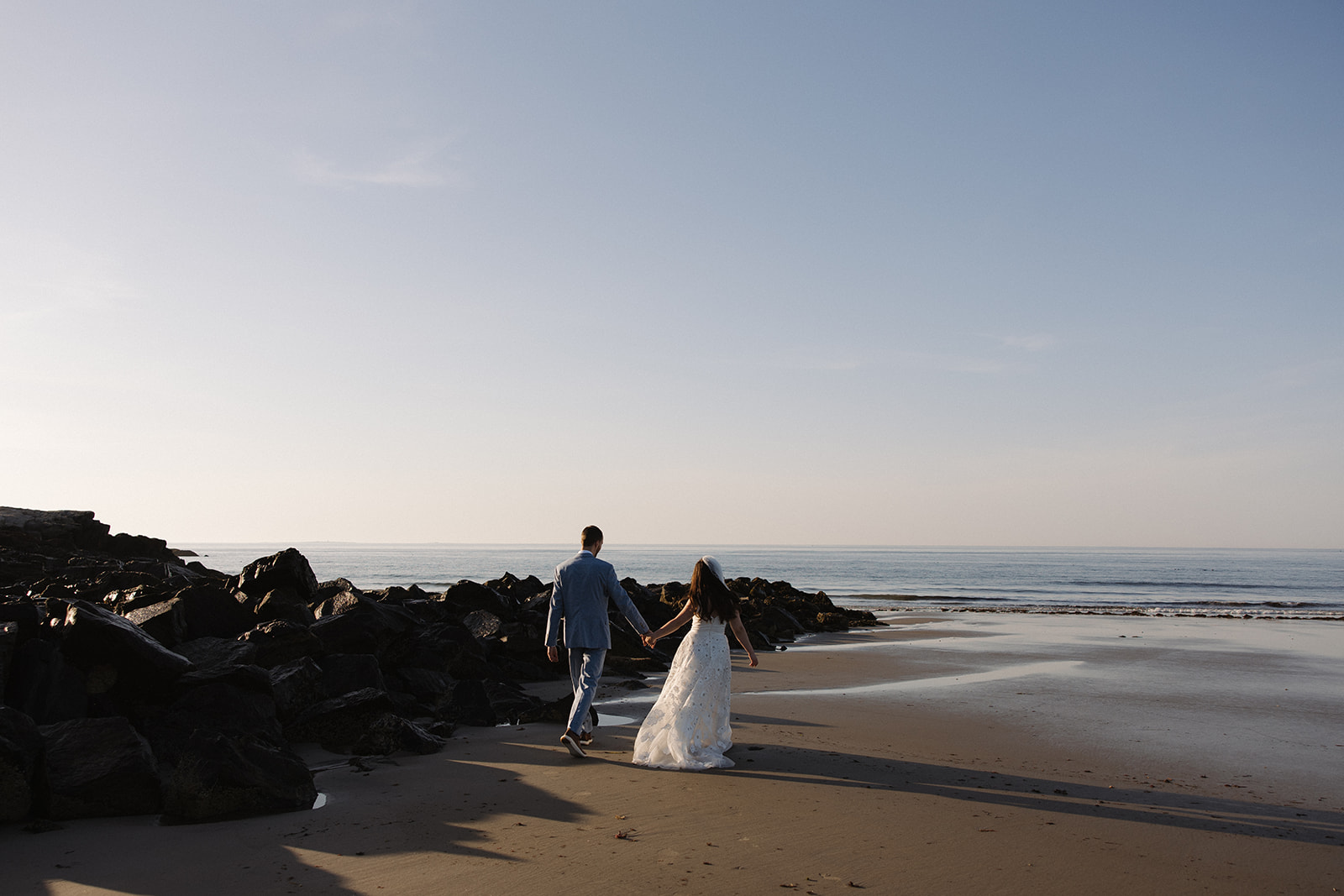 bride and groom share candid romantic moments during their first look session on the New Hampshire beach