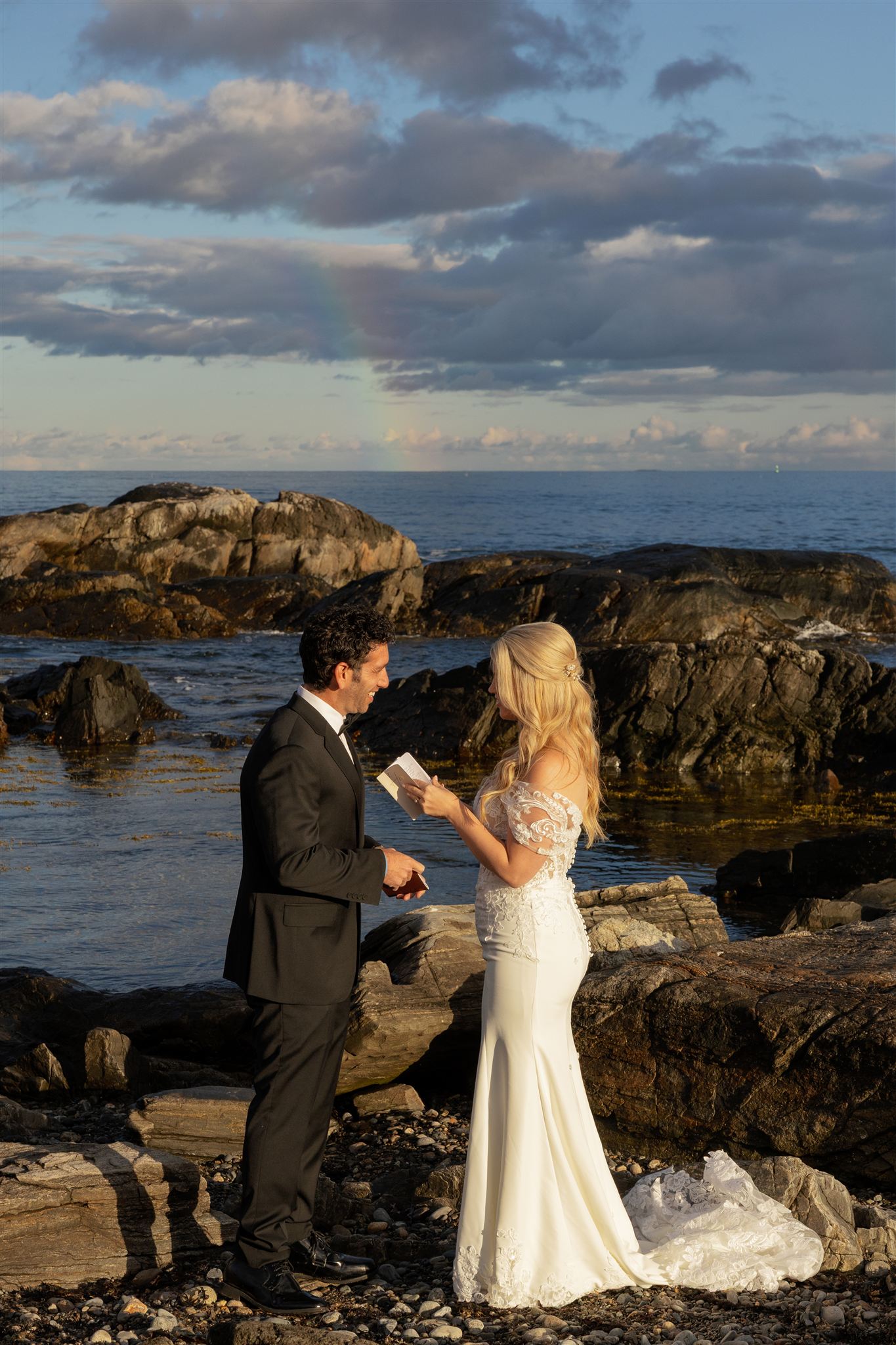 stunning bride and groom take a photo by the coast during their post wedding photoshoot