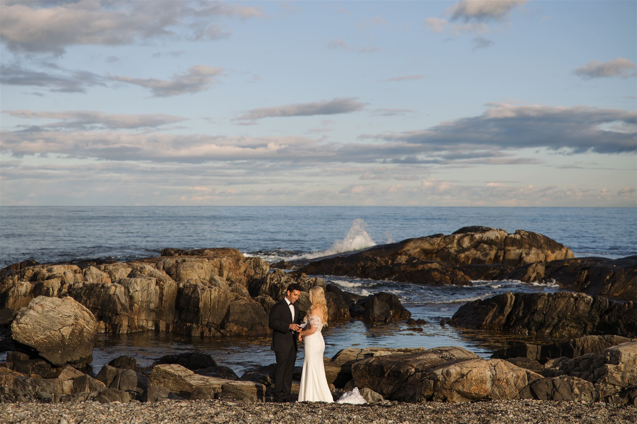 stunning bride and groom take a photo by the coast during their post wedding photoshoot