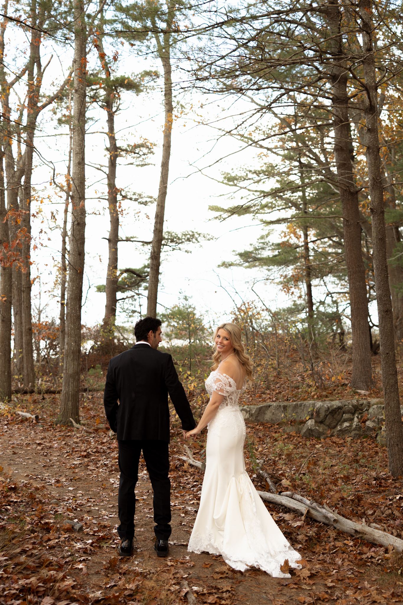bride and groom share a laugh as they walk through the fall woods together