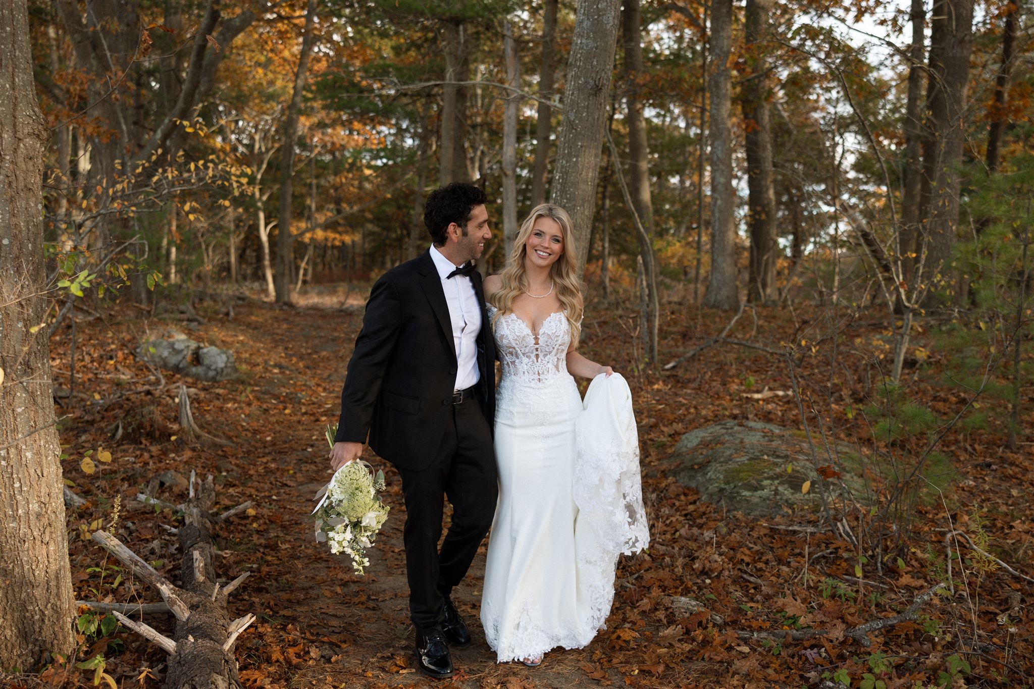 bride and groom share a laugh as they walk through the fall woods together