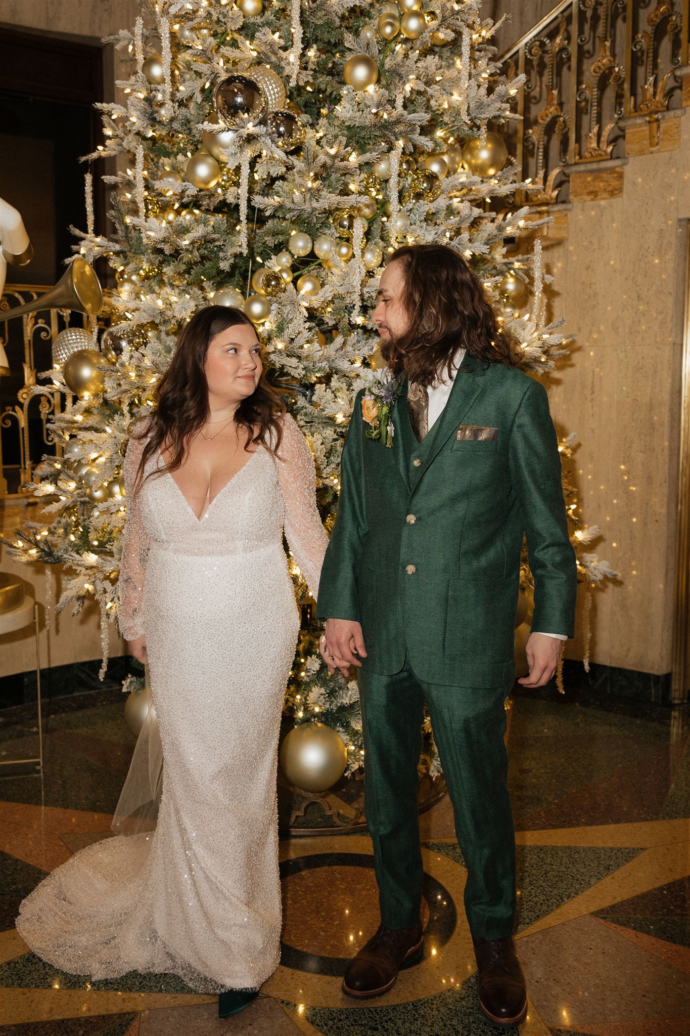 bride and groom walk together by the stunning Christmas tree, having your elopement around a holiday is a great way to make your elopement special
