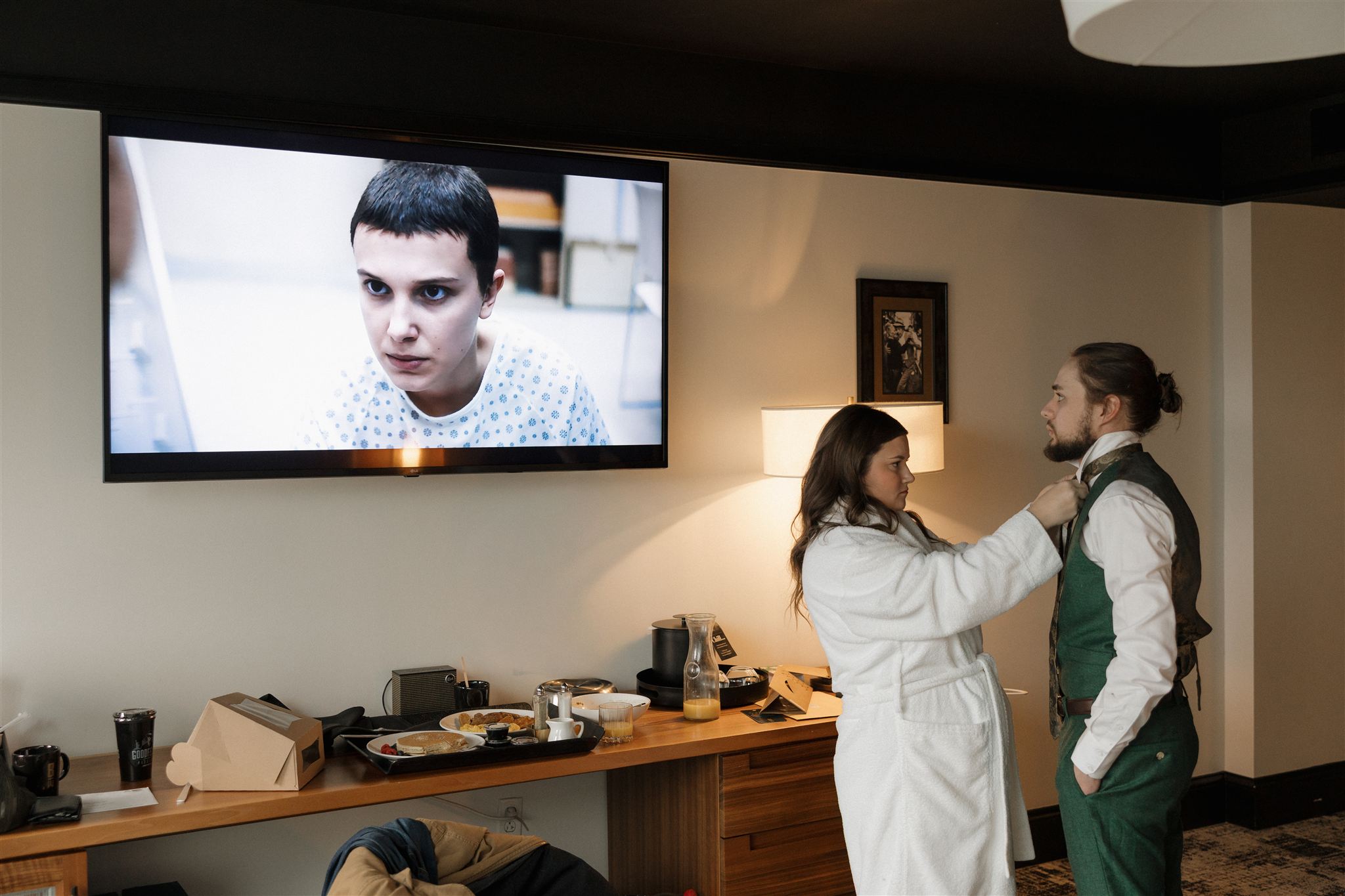 bride helps groom tie his tie as stranger things play in the background