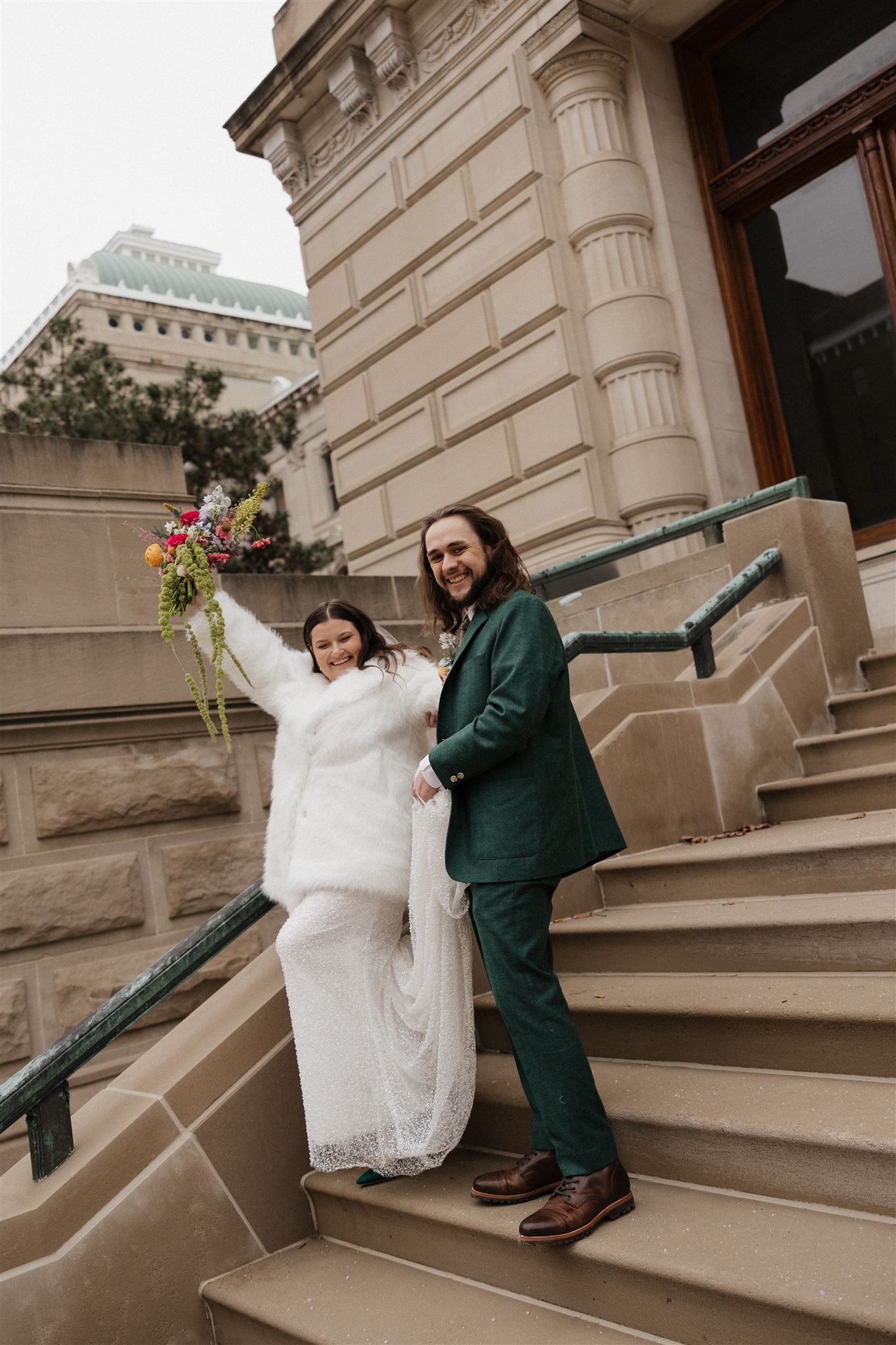 beautiful couple walk down the stairs smiling and celebrating their unique city elopement