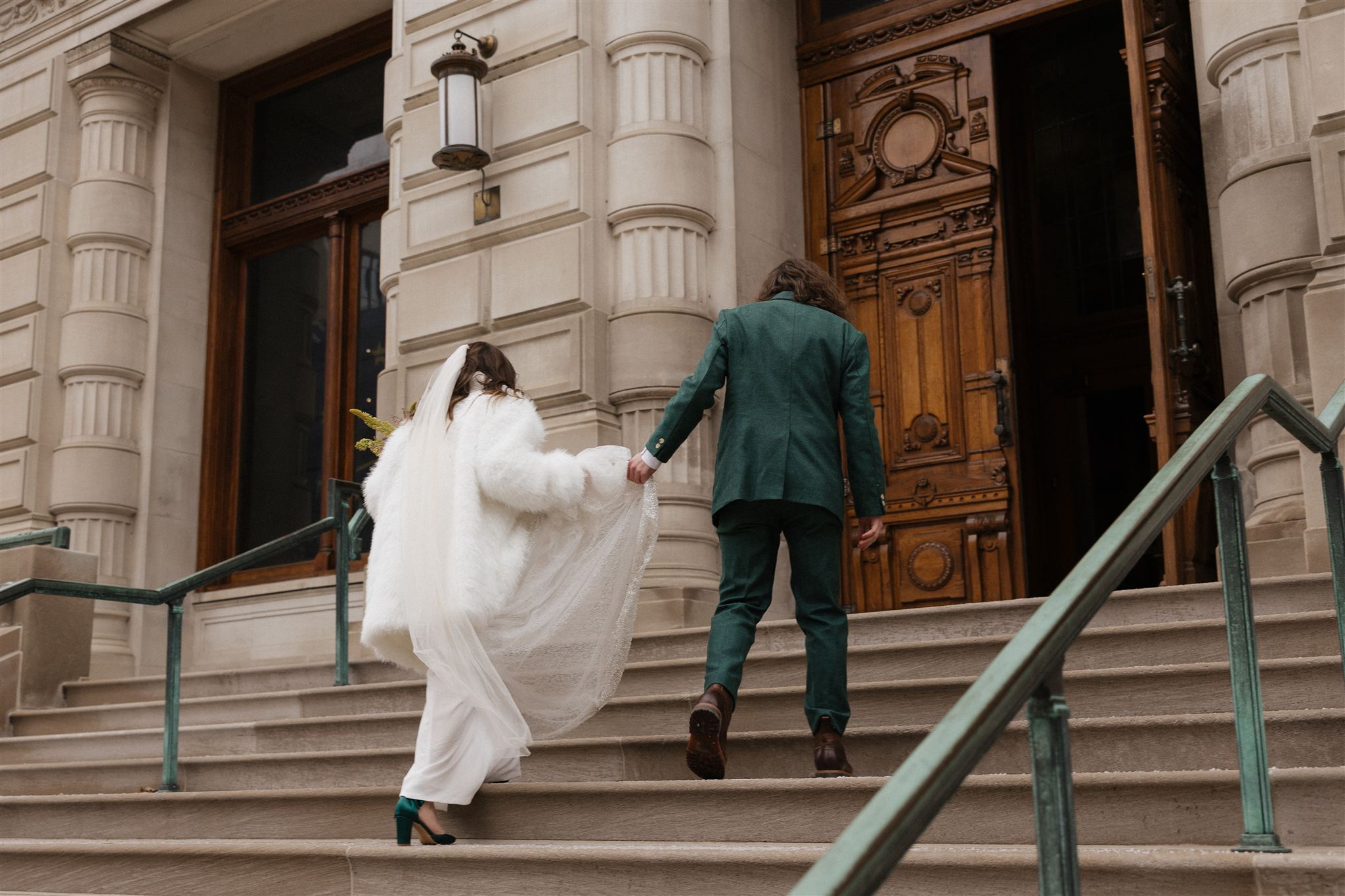 groom helps his bride carry her dress up the state house steps