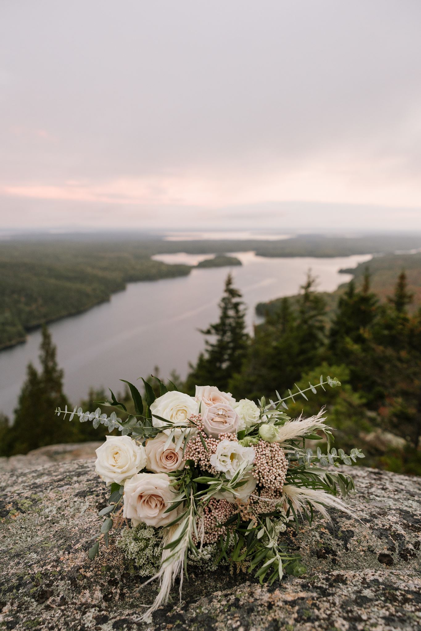 brides bouquet sits on a rock cliff with the lake in the background