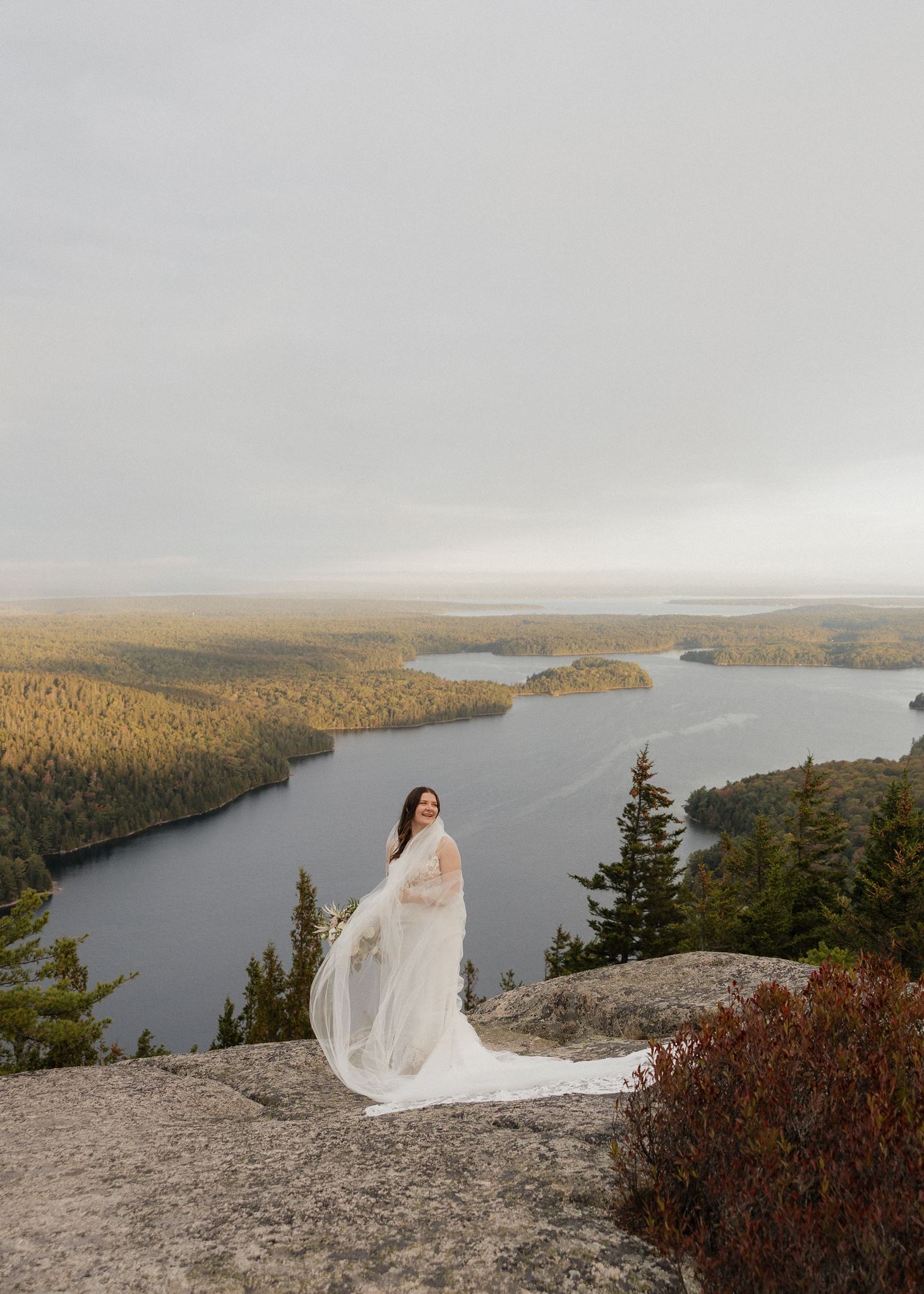 stunning bride poses for a photo with the lake in the backround