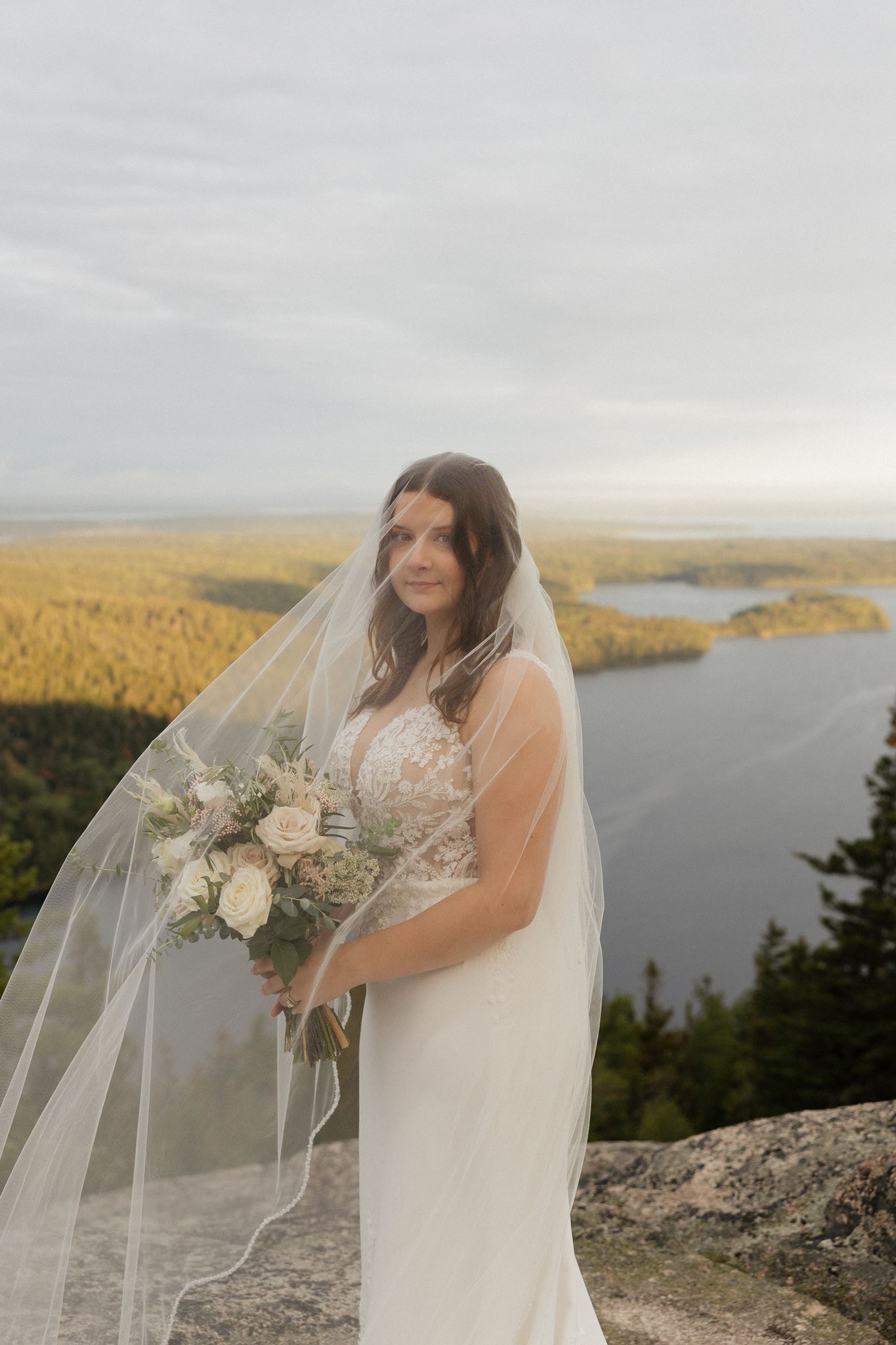 stunning bride poses for a photo with the lake in the backround