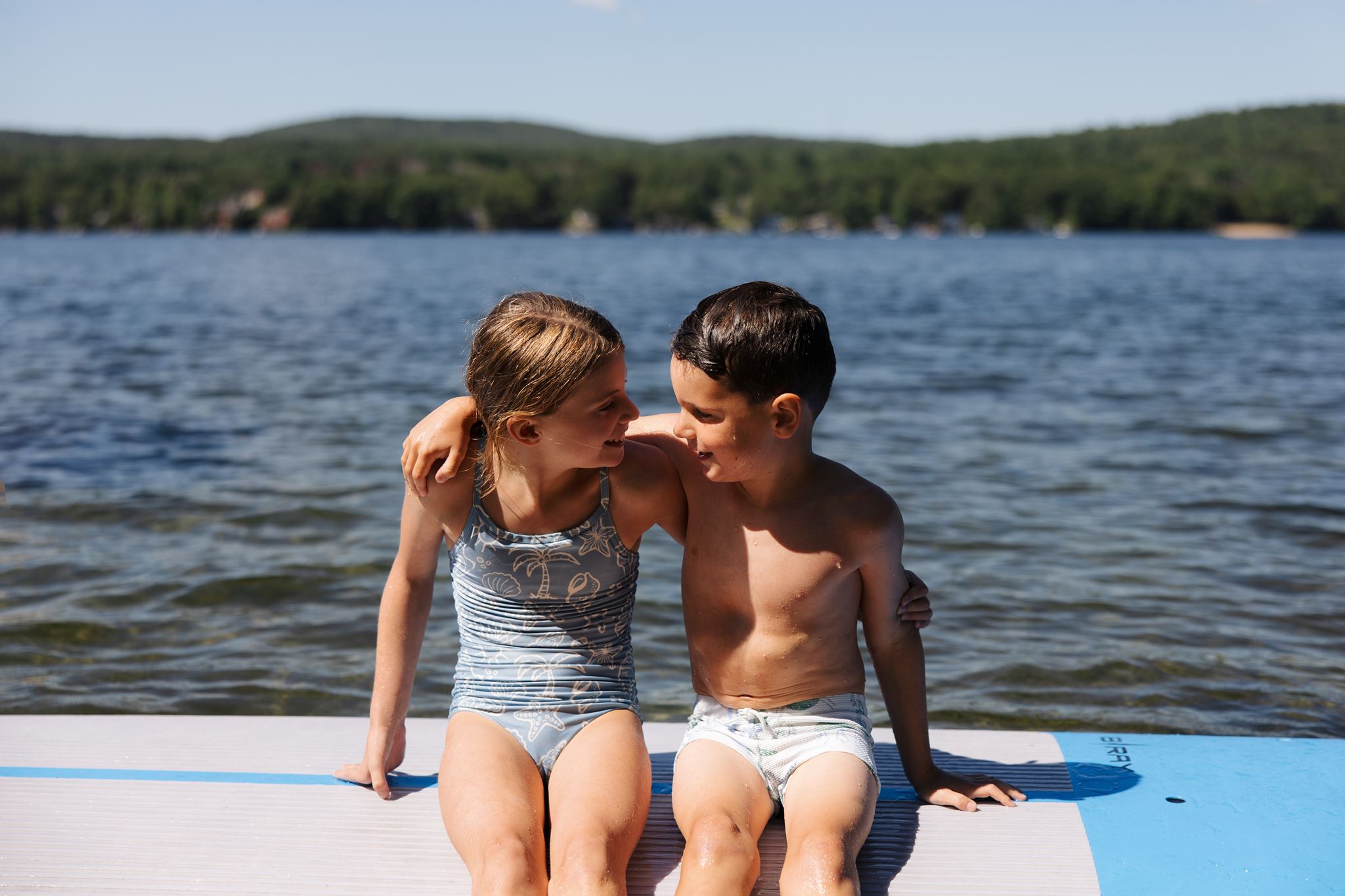 brother and sister embrace on the paddleboard