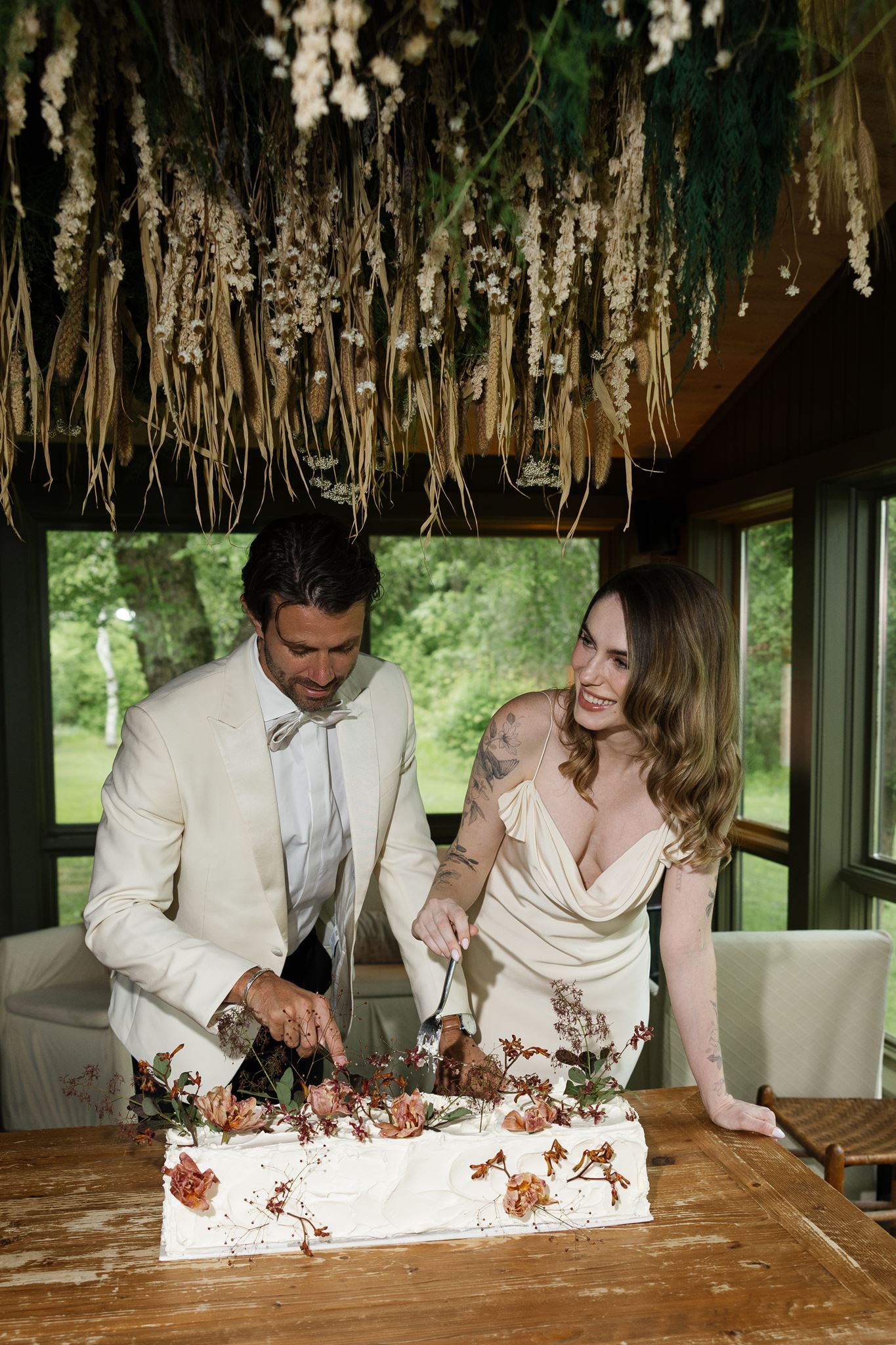 bride and groom cut their cake on with their floral whimsical style an intimate wedding